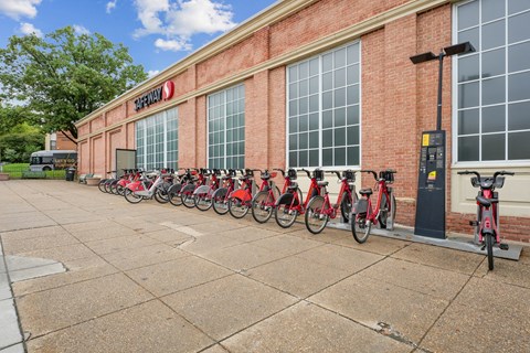 A row of red bikes are parked outside a building with a sign that says